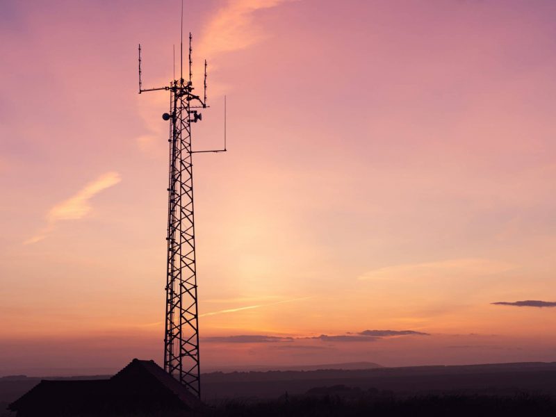 A vertical shot of a telecom tower in a field under the breathtaking sky -perfect for wallpaper